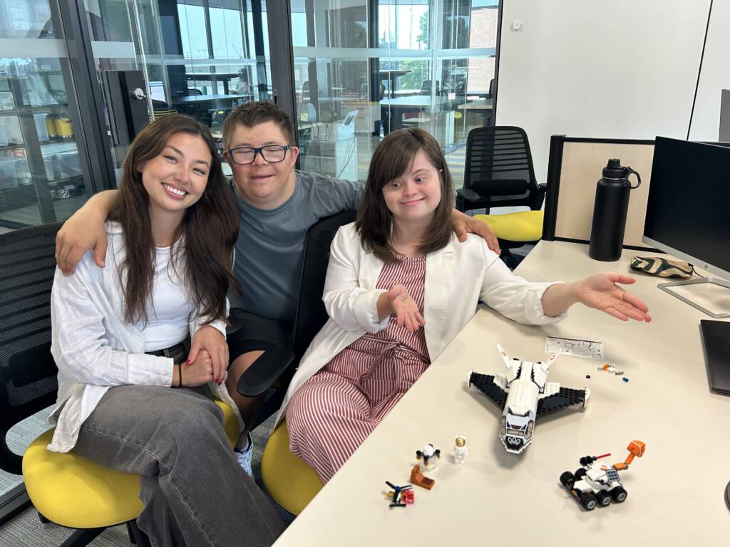 Three individuals smiling with their LEGO that they built